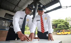 Dos guardias de seguridad privada de Fortox revisan documentos juntos en una mesa, centrados en labores de vigilancia. - Fortox