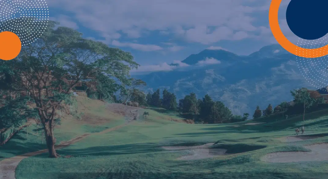 En la imagen se observa un campo de golf con césped verde, trampas de arena y grandes árboles. Al fondo destacan bajo montañas un cielo parcialmente nublado. En las esquinas superiores aparecen círculos gráficos decorativos. No hay personal de seguridad privada, vehículos o edificios visibles en la escena; el enfoque principal es el paisaje natural del campo de golf. - Fortox Security
