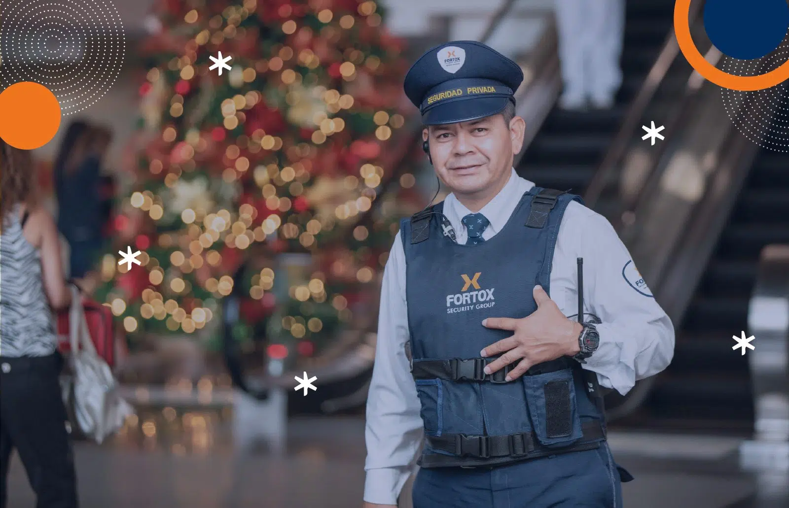 Guardia de seguridad privada Fortox vigila junto a escalera eléctrica y árbol de Navidad en centro comercial durante la temporada navideña. - Fortox Security