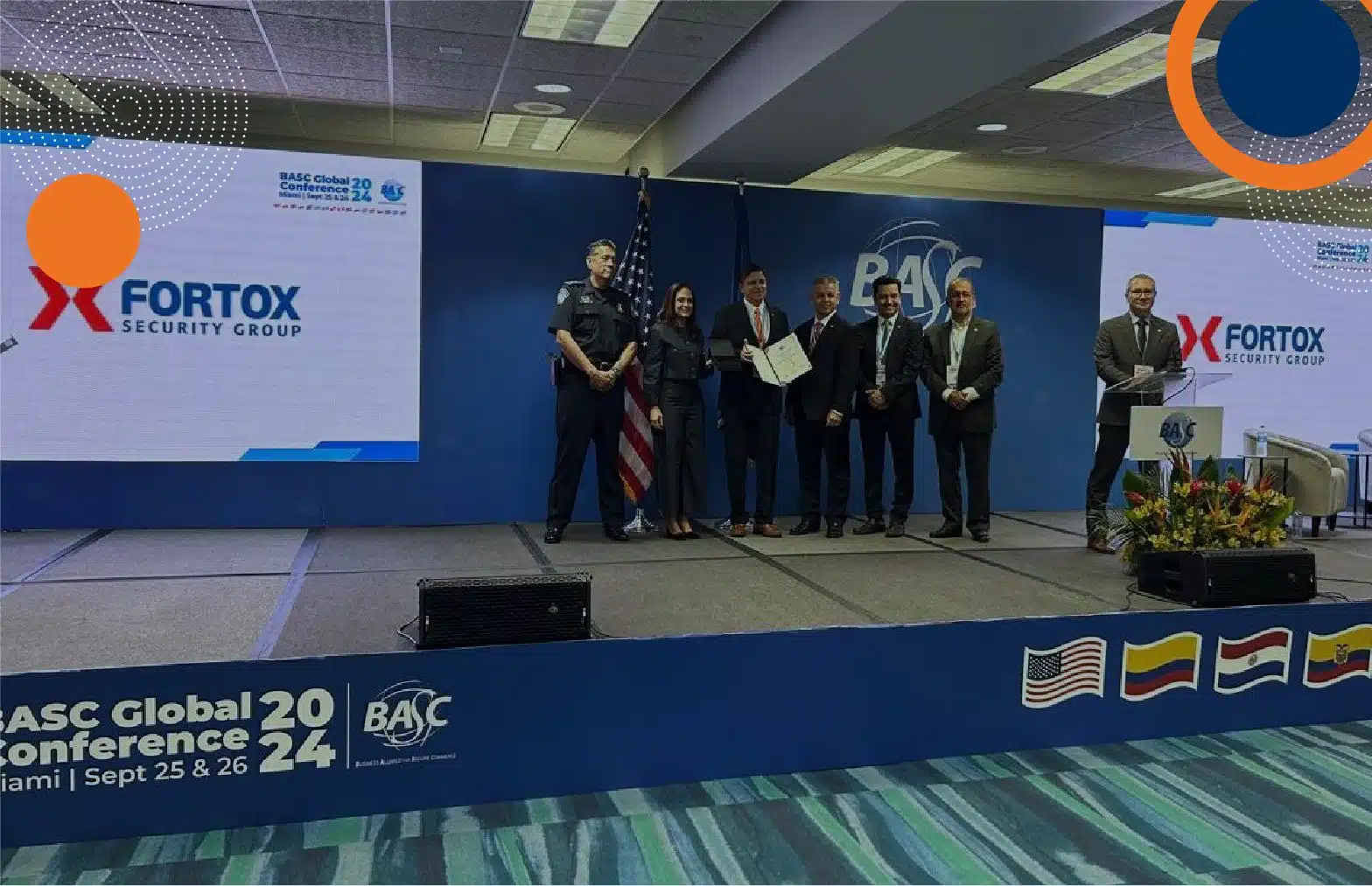 Grupo de seguridad privada Fortox recibe reconocimiento internacional en conferencia BASC, con directivos y pantalla al fondo. - Fortox Security