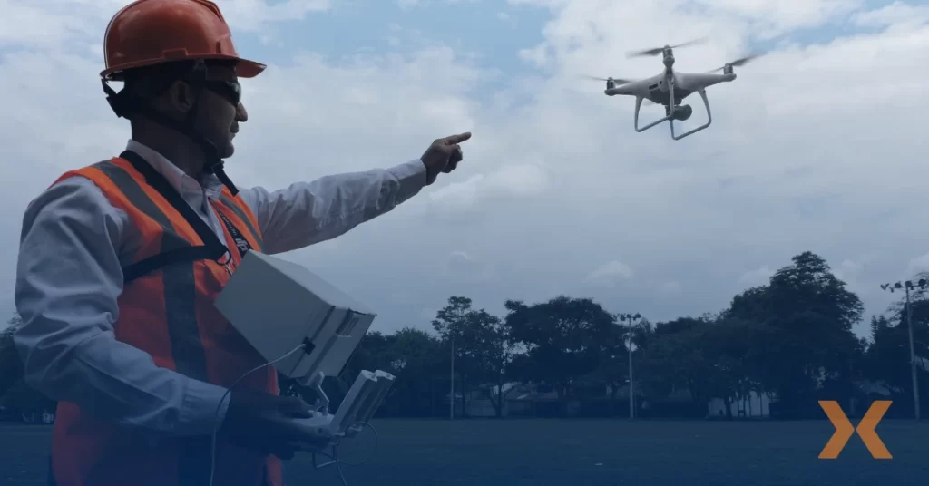 Persona con casco y chaleco de seguridad opera un dron, vigilancia tecnológica de Fortox en exteriores con árboles y cielo nublado. - Fortox Security