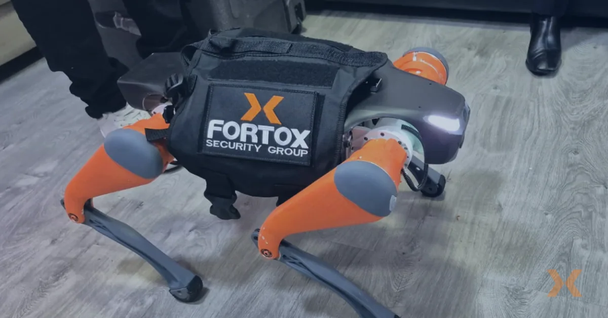 Robot de seguridad Fortox con patas naranjas y grises en piso interior, tecnología para vigilancia y seguridad privada. - Fortox