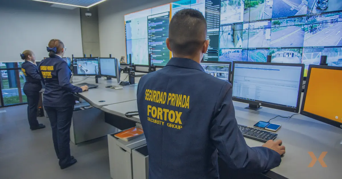 Personal de seguridad privada Fortox monitorea pantallas de vigilancia en la sala de control, protegiendo empresas. - Fortox